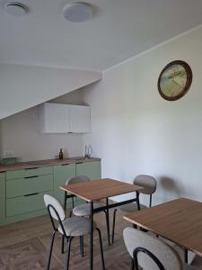 a kitchen with two tables and chairs and a clock on the wall at Niwy8Rooms in Oświęcim