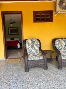two wicker chairs sitting next to a yellow wall at Pousada Belvedere da Serra in Serra do Cipo