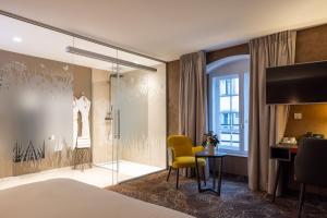 a bedroom with a bed and a table and a window at Hotel Restaurant L'Orchidee in Ensisheim