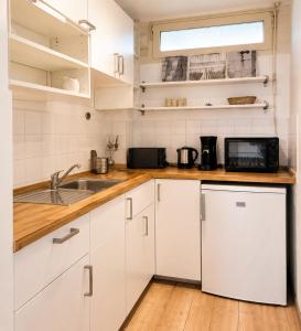 a kitchen with white cabinets and a sink and a microwave at Strandläufer in Wendtorf