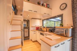 a kitchen with white cabinets and a clock on the wall at Gemütliches Tiny House mit Terrasse & Klima an Badesee & Naturpanorama für max 4 Gäste in Salzhemmendorf +14 photos
