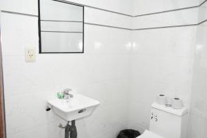 a white bathroom with a sink and a toilet at Nexus Hotel & Coworking in Copacabana