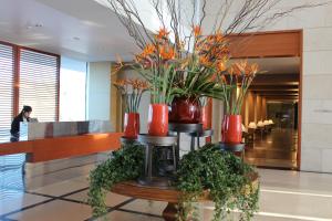 a lobby with red vases with plants on a table at First Class Marina Herzlia in Herzelia 