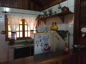 a kitchen with a refrigerator with a chef on it at Chalé Pura Vida - Casa de madeira no centro in São Roque de Minas
