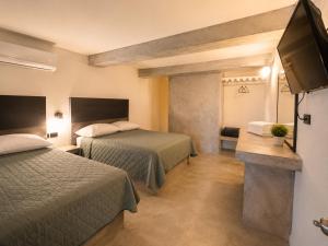 a hotel room with two beds and a flat screen tv at Hotel Miramar - La Paz in La Paz