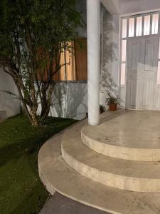 a porch with a white door and a tree at casa granada en Carranza in San Luis Potosí