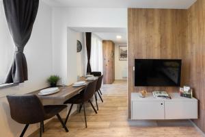 a dining room with a table with chairs and a tv at Apartmány Stožec - Nella Premium in Stožec