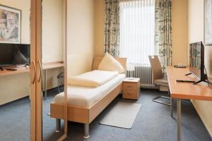 a room with a bed and a desk and a television at Hotel Romäus in Villingen-Schwenningen