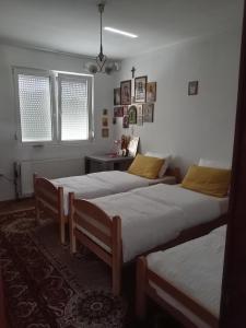 two beds in a room with a table and windows at Sobe Andjela in Arilje