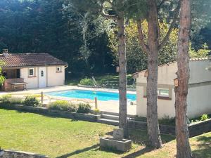 a swimming pool in a yard next to a house at Studio indépdendant dans un parc verdoyant avec piscine in Andrézieux-Bouthéon