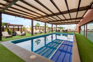 an outdoor swimming pool with a pergola and a patio at Barcelo Guadalajara in Guadalajara