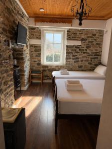 ein Schlafzimmer mit einem Bett in einem Zimmer mit einer Ziegelwand in der Unterkunft Vila Drasa Guesthouse in Gjirokastër