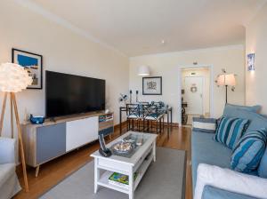 a living room with a blue couch and a flat screen tv at Atlantic Ocean View Apartment in Funchal