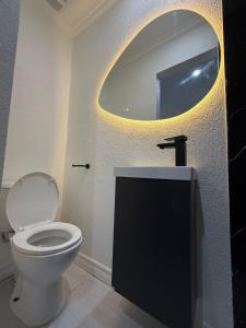 a bathroom with a toilet and a round mirror at The Hideaway Cabin Barbados in Christ Church