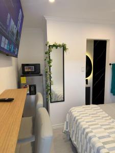a room with a bed and a table and a mirror at The Hideaway Cabin Barbados in Christ Church