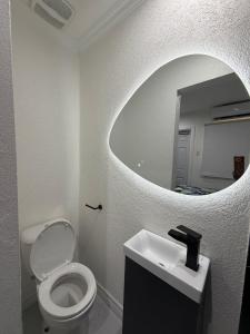 a bathroom with a white toilet and a mirror at The Hideaway Cabin Barbados in Christ Church