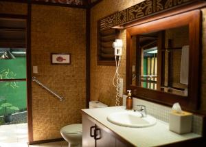 a bathroom with a sink and a toilet and a mirror at Rarotonga Beach Bungalows in Rarotonga