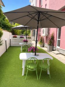 a table and chairs with an umbrella on a lawn at Hotel Alexander in Sofia