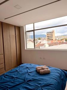 a bedroom with a blue bed with a large window at Departamento CENTRICO CENTRO LOJA in Loja