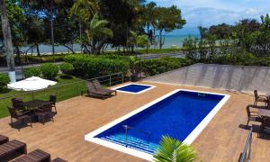 a pool on a wooden deck with chairs and a table at Porto Cálem Praia Hotel in Porto Seguro