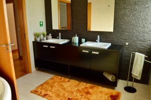 a bathroom with two sinks and a brown rug at Cantinho do Minho - Ponte de Lima in Ponte de Lima