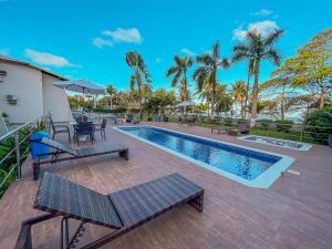 a swimming pool with tables and chairs and palm trees at Porto Cálem Praia Hotel in Porto Seguro
