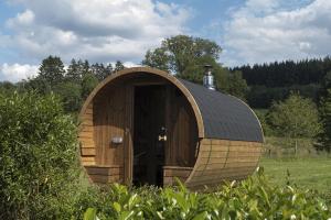 a wooden cabin with a black roof in a field at Chambres Ardennez-vous in Saint-Hubert