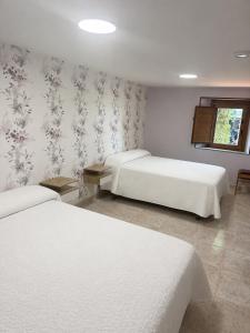 a bedroom with two beds and a wall with floral wallpaper at Casa Estraviz in A Coruña