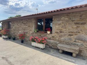 a stone building with potted plants and a bench at Casa Estraviz in A Coruña