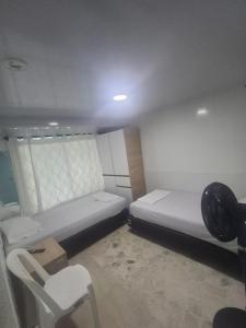 a small room with two beds and a chair at Posada El Carro Amarillo SAS in Floridablanca
