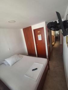 a bedroom with a white bed with a pen on it at Posada El Carro Amarillo SAS in Floridablanca +4 photos