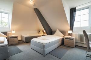 a room with two beds and a chair and two windows at Hotel Romäus in Villingen-Schwenningen