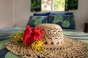 a straw hat with a flower on a bed at Bungalow Tearo in Tiripoa