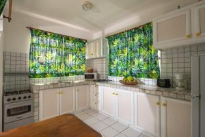 a kitchen with white cabinets and tropical windows at Bungalow Tearo in Tiripoa