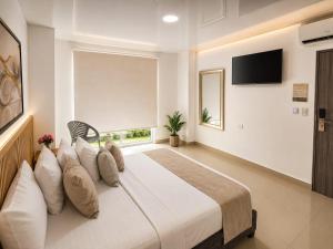 a bedroom with a large white bed with a window at Hotel Gama Cartagena in Cartagena de Indias