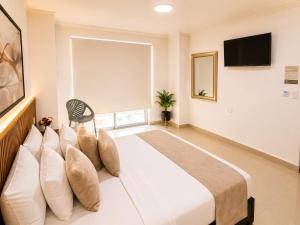 a bedroom with a large white bed with pillows at Hotel Gama Cartagena in Cartagena de Indias