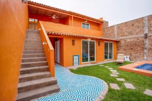 an orange house with a swimming pool and stairs at Riberas Suites in Chapala