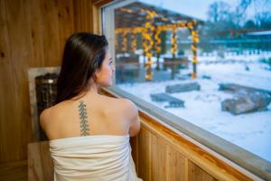 a woman looking out a window with a tattoo on her back at Wellness Glamping Apartmán Přerov in Přerov
