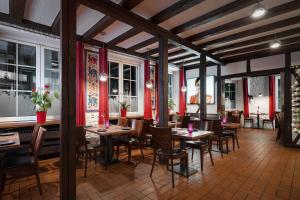 a restaurant with wooden tables and chairs and red curtains at Hotel Romäus in Villingen-Schwenningen