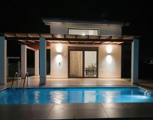 a swimming pool in front of a house at night at Nerina House in Paralia Katerinis