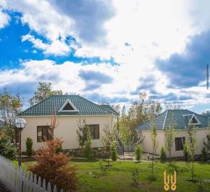 a white house with a fence in a yard at WhiteHotelGabala in Gabala