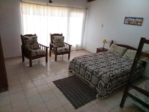 a bedroom with a bed and two chairs and a window at Hospedaje Nely in San Vicente