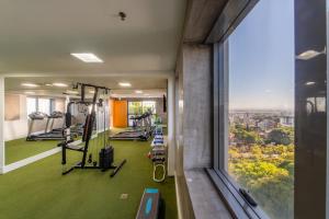a gym with a green floor and a large window at Hotel Laghetto Stilo Higienópolis in Porto Alegre