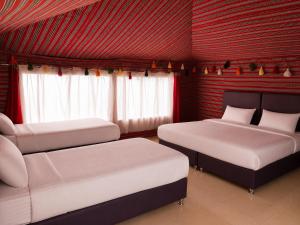 two beds in a room with red walls at Starry Nights Camp in Wadi Rum +8 photos