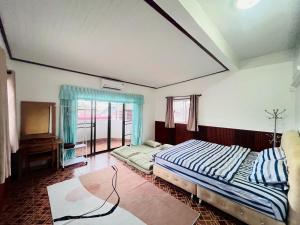 a bedroom with two beds and a tv in it at The Warm House in Ban Komo Sip Paet