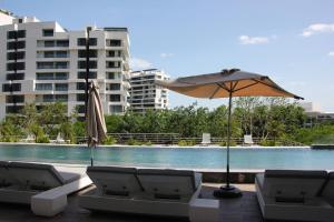 a pool with two lounge chairs and an umbrella at Panoramic Lake View Cabo Norte Mérida in Mérida