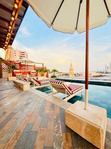 a pool with tables and chairs and an umbrella at NH Royal Urban Cartagena in Cartagena de Indias +40 photos