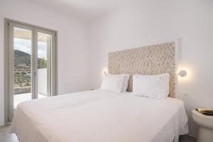a white bedroom with a white bed and a window at Villa Serenity Complex in Kampos Paros +99 photos