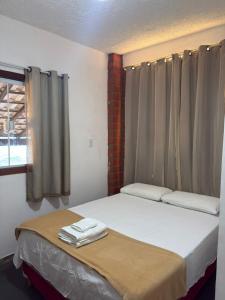 a bed in a room with curtains and a window at Suites Prime in Marataizes
