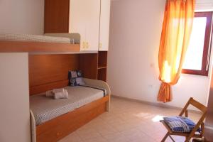 a bedroom with bunk beds and a chair and a window at Casa Elena Floris in Teulada